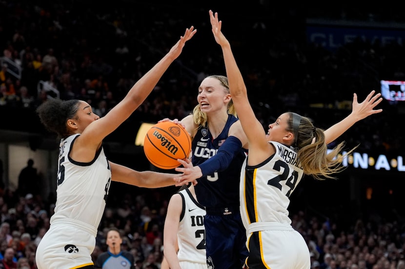 UConn guard Paige Bueckers, center, drives between Iowa forward Hannah Stuelke, left, and...