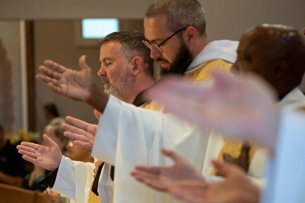 Priests pray during a Mass at Sacred Heart Church in...
