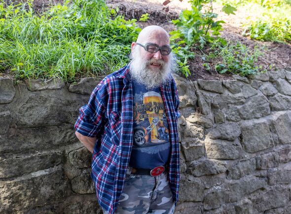 Moz Needham leans against a stone wall