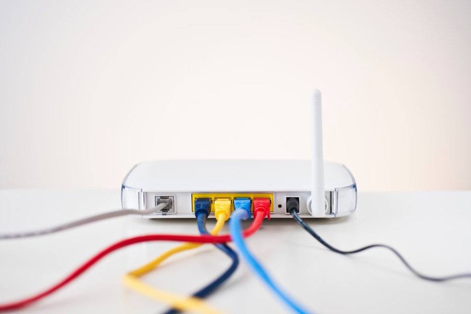 A white router with colorful ethernet cables plugged into it.