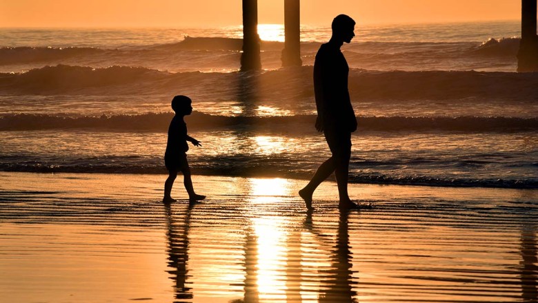 A father and son stroll next to the Ocean Beach Pier at sunset. Photo by Chris Stone