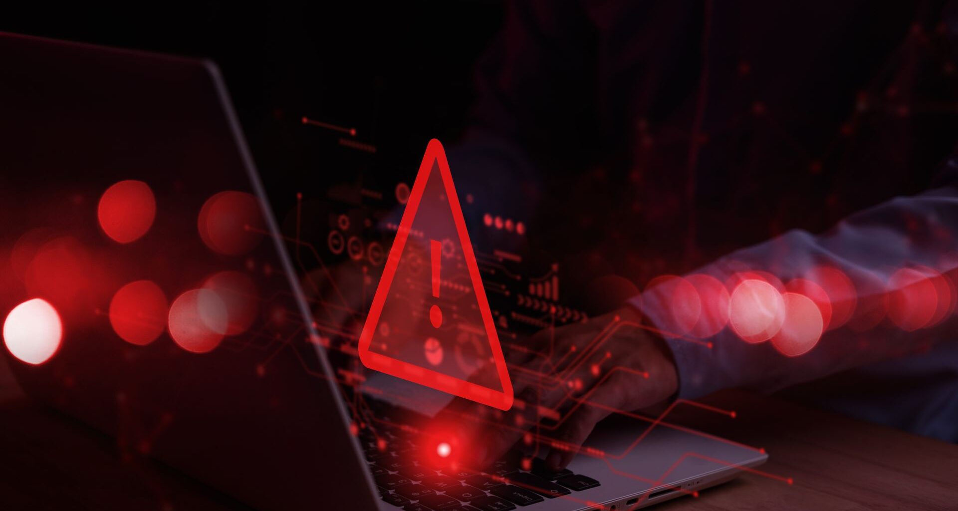 Laptop with warning symbol in red denoting a cyber attack or compromised device.