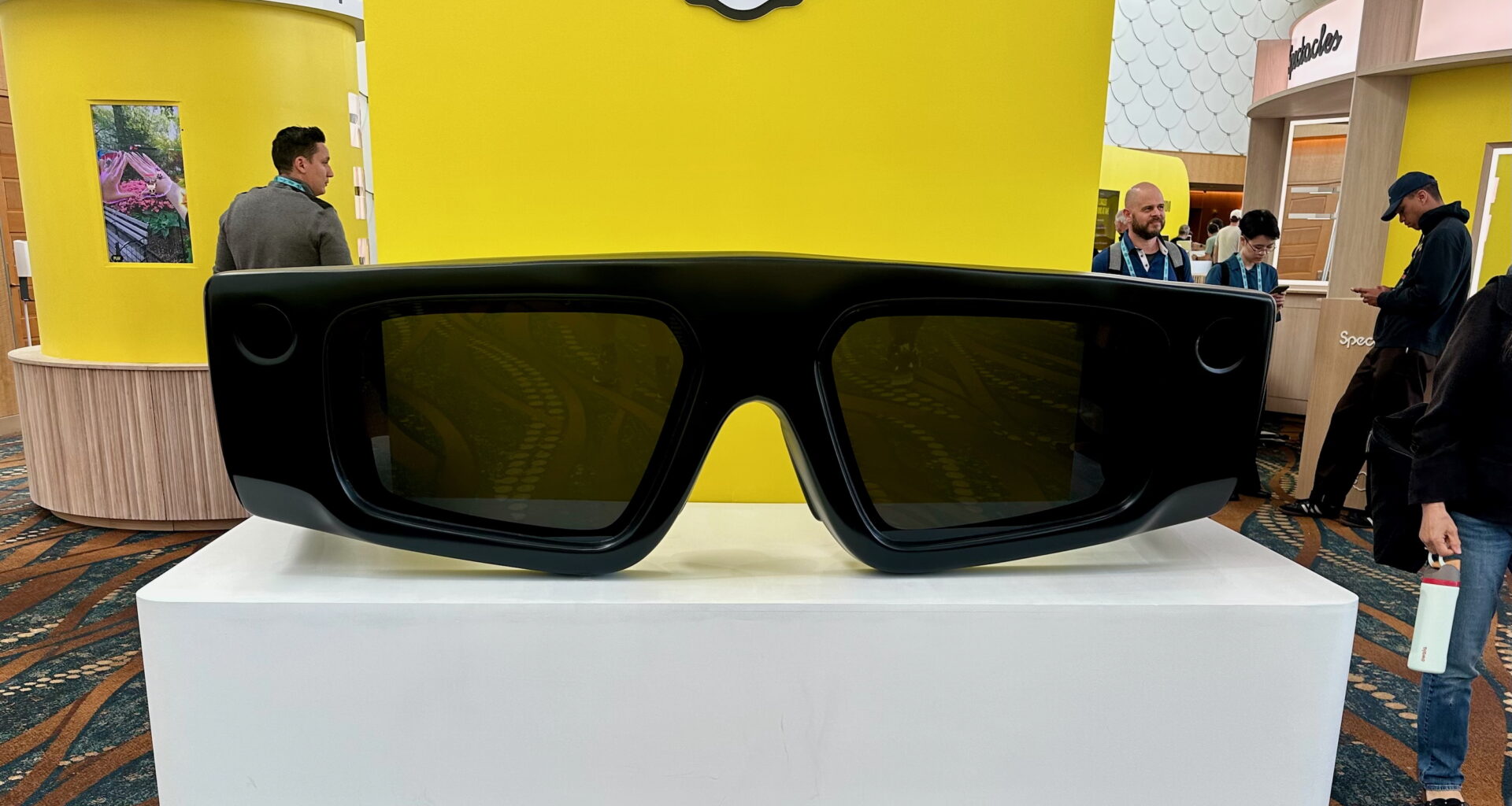 A giant-sized pair of Snap Spectacles AR glasses facing the photographer, on a podium on the AWE 2025 show floor.