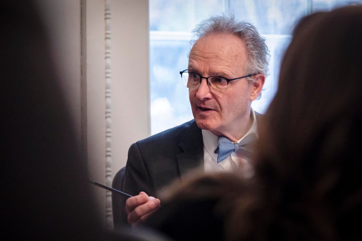 A man in a suit and tie is talking to a group of people.