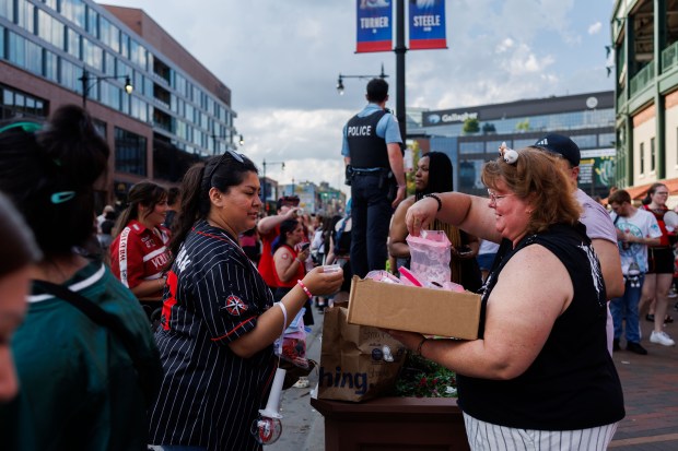 From left, Kassandra Lopez, 29, trades freebies - small photos, candy, or stickers - with Laura Levy, 57, from Wisconsin, outside Wrigley Field before the Stray Kids concert on June 26, 2025. (Armando L. Sanchez/Chicago Tribune)