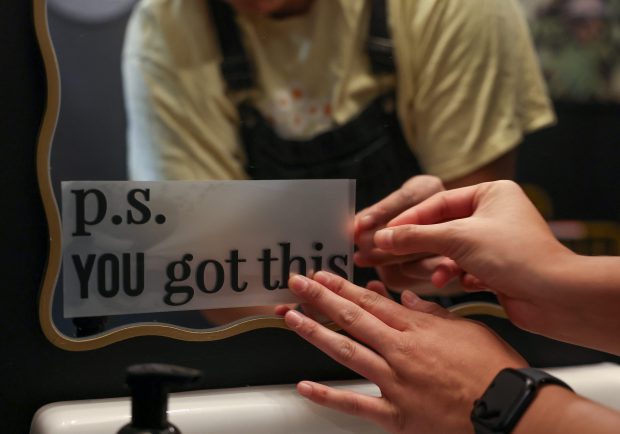 A staff member applies a decal to a mirror in the bathroom at Hope Clinic on May 28, 2025, in Chicago. (Stacey Wescott/Chicago Tribune)