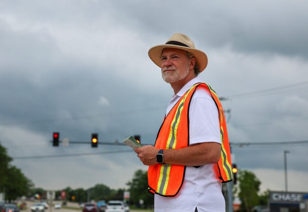 Eric Scheidler, the executive director of the Pro-Life Action League, hands out pro-life literature to stopped vehicles near Rand Road and Illinois Route 22 in Lake Zurich as part of a six-day Face the Truth Tour on June 18, 2025. Scheidler said while abortion at any point is unconscionable, terminations later in pregnancy are particularly abhorrent. (Stacey Wescott/Chicago Tribune)