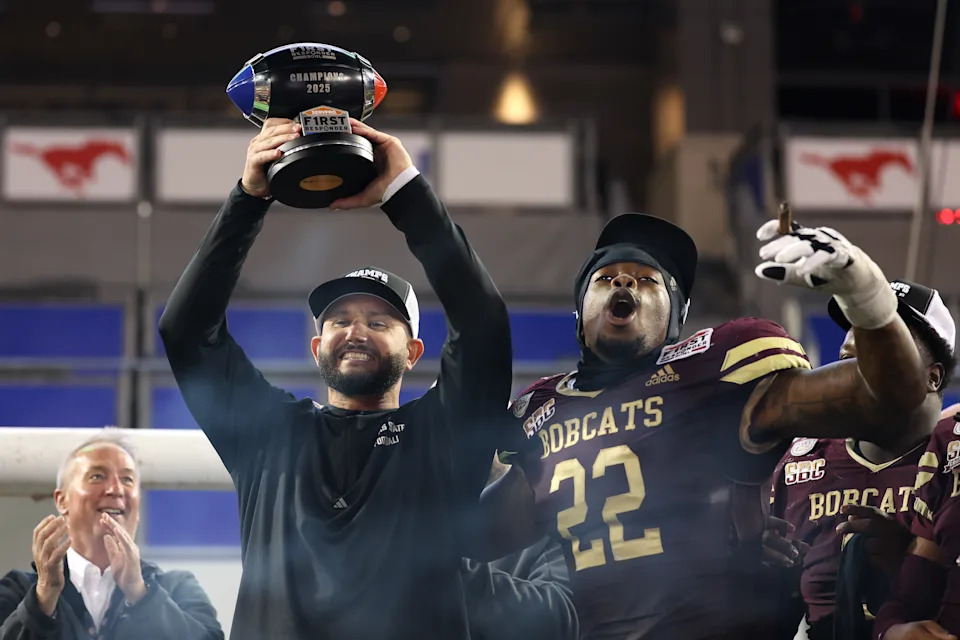 DALLAS, TEXAS - JANUARY 03: Head coach GJ Kinne of the Texas State Bobcats lifts the trophy and celebrates with Kalil Alexander #22 after defeating the North Texas Mean Green in the \sfr at Gerald J. Ford Stadium on January 03, 2025 in Dallas, Texas. (Photo by Sam Hodde/Getty Images)