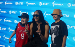 Three individuals pose in front of a WNBA and AT&T logo backdrop.