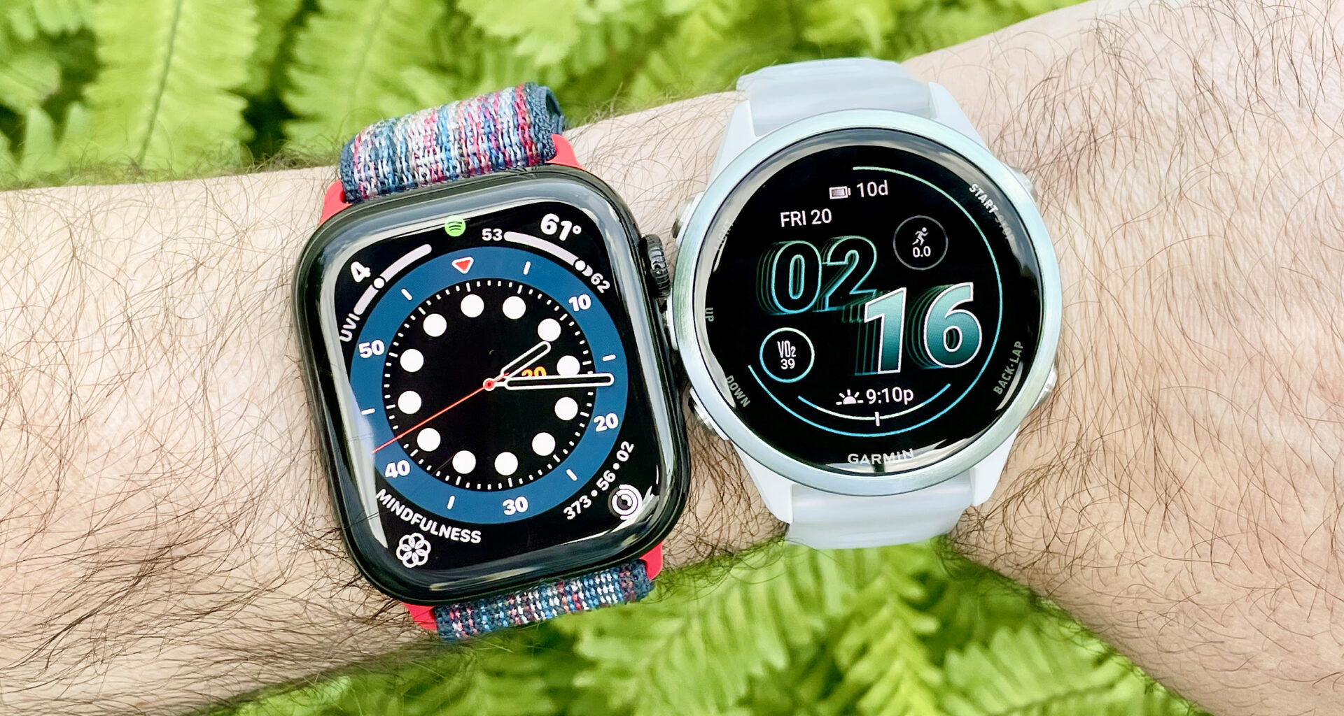 Apple Watch Series 10 next to a Garmin Forerunner 570 on a user's wrist with green foliage out of focus in the background