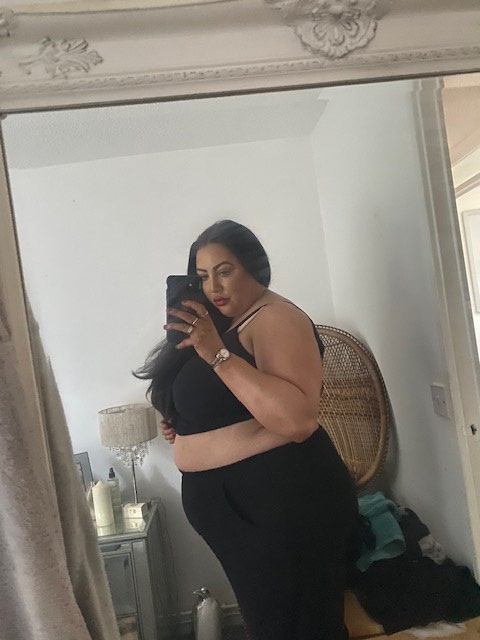 Woman taking a mirror selfie, showing her weight loss.