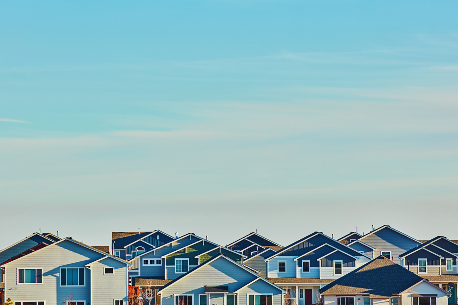 Image of the top of houses and a blue sky.