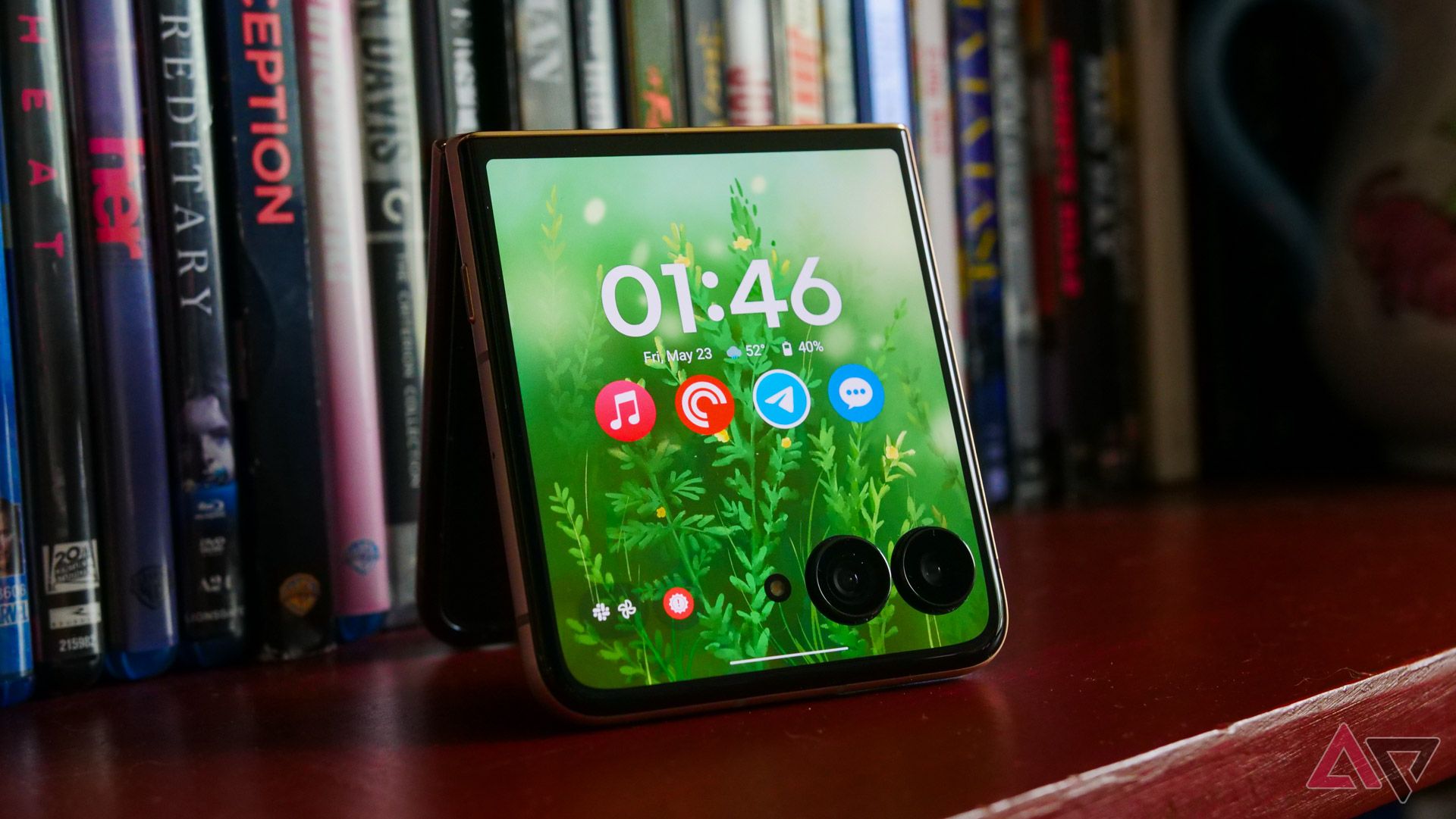 The Moto Razr Ultra with its cover display on resting on a bookcase.