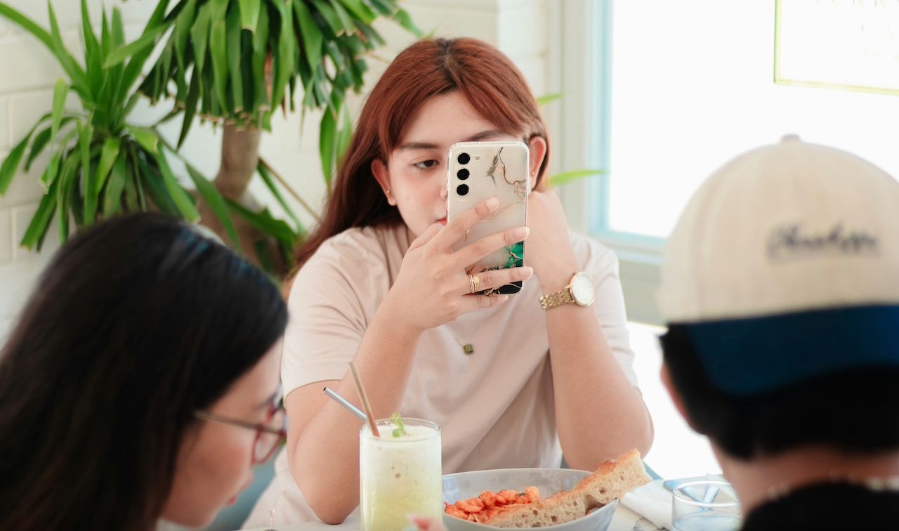 Girl using Samsung phone with food in front of her