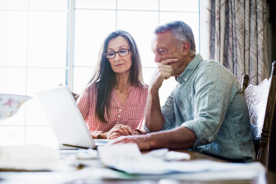 Senior couple using a laptop at their dining table.