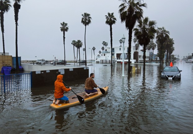 Flooding in many parts of San Diego in January 2024 showed huge problems with city storm infrastructure. Above, Kolby Qualls, front, and Evan Anderson paddle across a flooded Abbott Street in Ocean Beach after a powerful storm. (K.C. Alfred / The San Diego Union-Tribune)