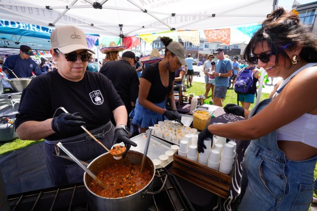 At the 45th Annual Ocean Beach Street Fair & Chili Cook-Off on Saturday, June 28, 2025, in San Diego, Lauren Alstrup (r) and Ana Buelna (l) served up samples of their chili from the La Doña restaurant. The group is competing in the restaurant division for the chili cook-off. (Nelvin C. Cepeda / The San Diego Union-Tribune)