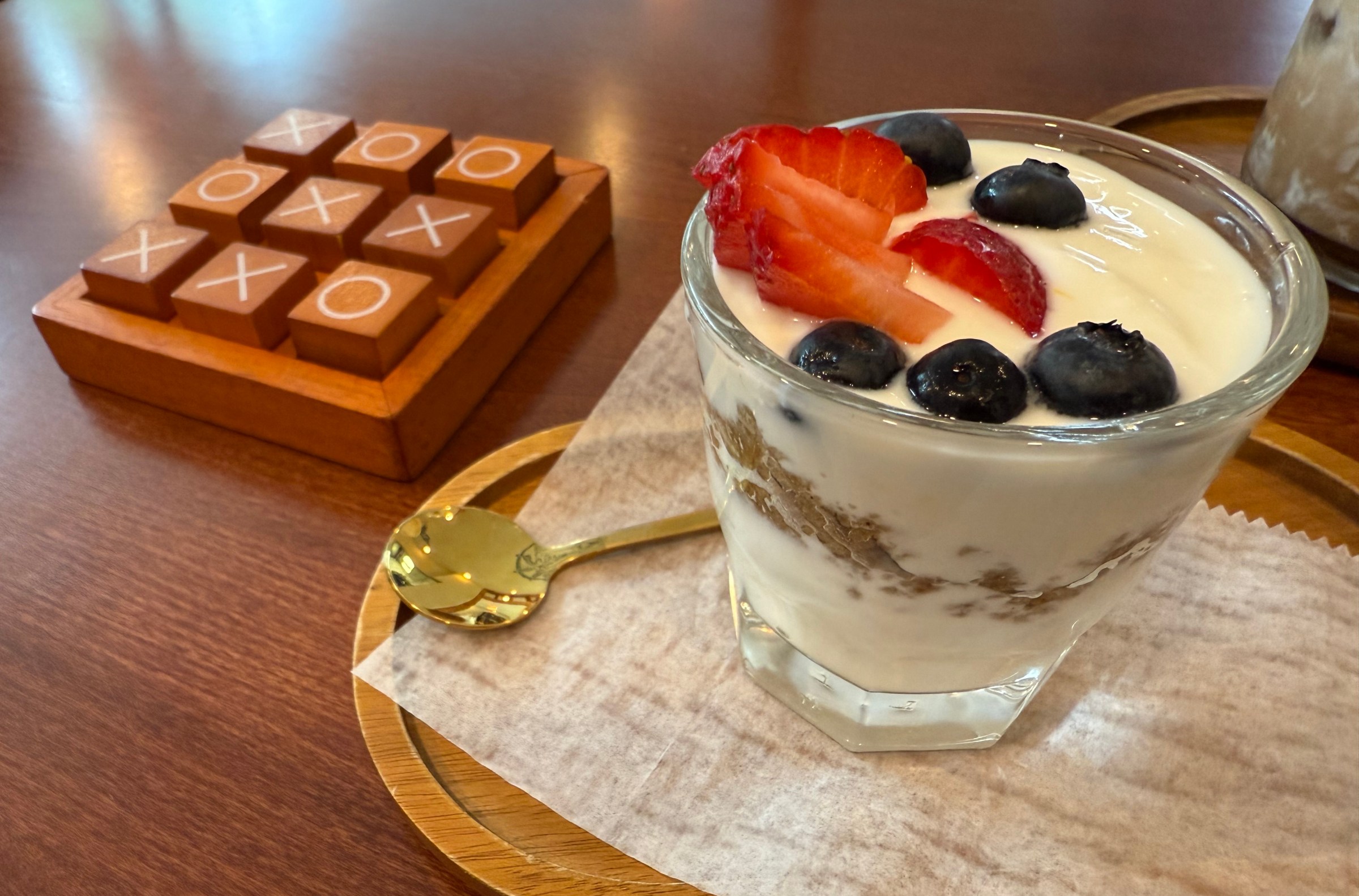 A parfait in a glass next to squares of food.