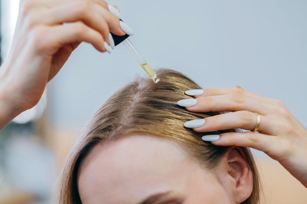 Woman applying serum to scalp
