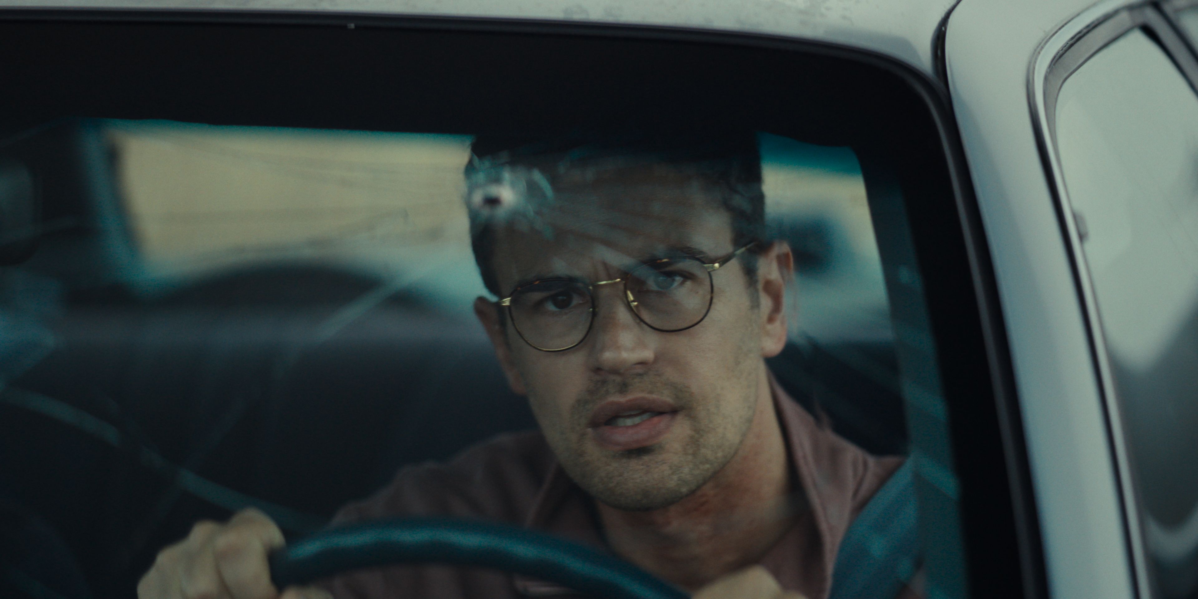 Theo James as Hal looking through windshield with a gunshot in it in Oz Perkins' The Monkey