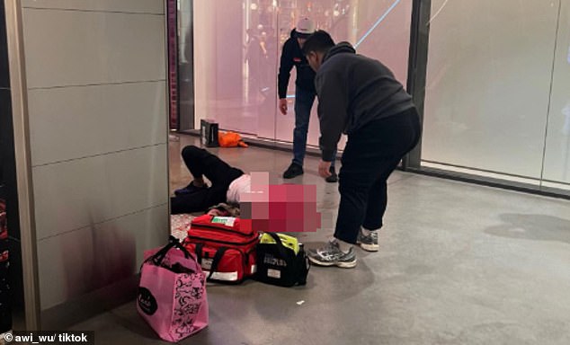 A witness shared a photo of paramedics treating the man as he lay on the ground (pictured)