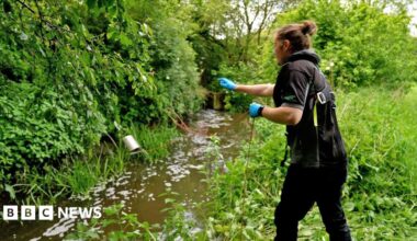 A man clad in a white jacket and wearing glasses conducts water testing at the Starcross laboratory in Devon.