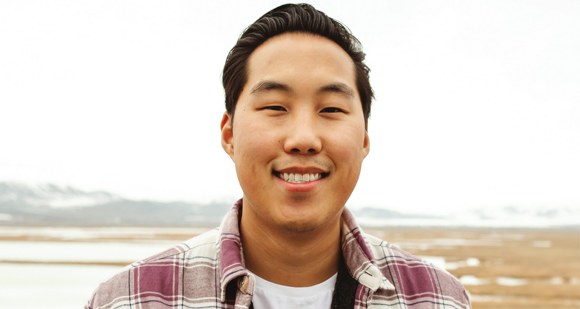 Preston Seo smiling outside with open land behind him