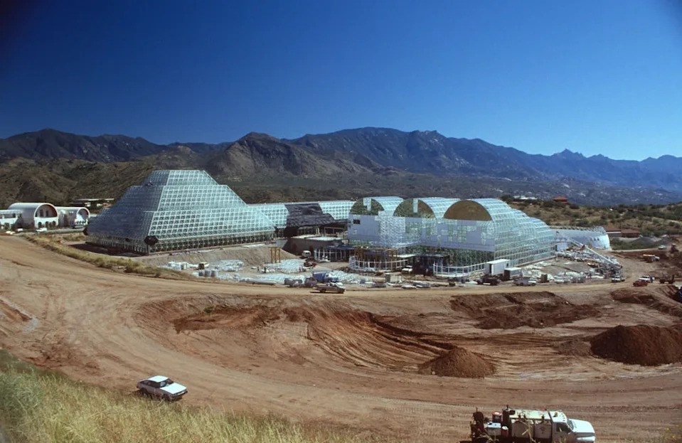 Biosphere 2 complex in an arid landscape, featuring futuristic glass structures with mountains in the background