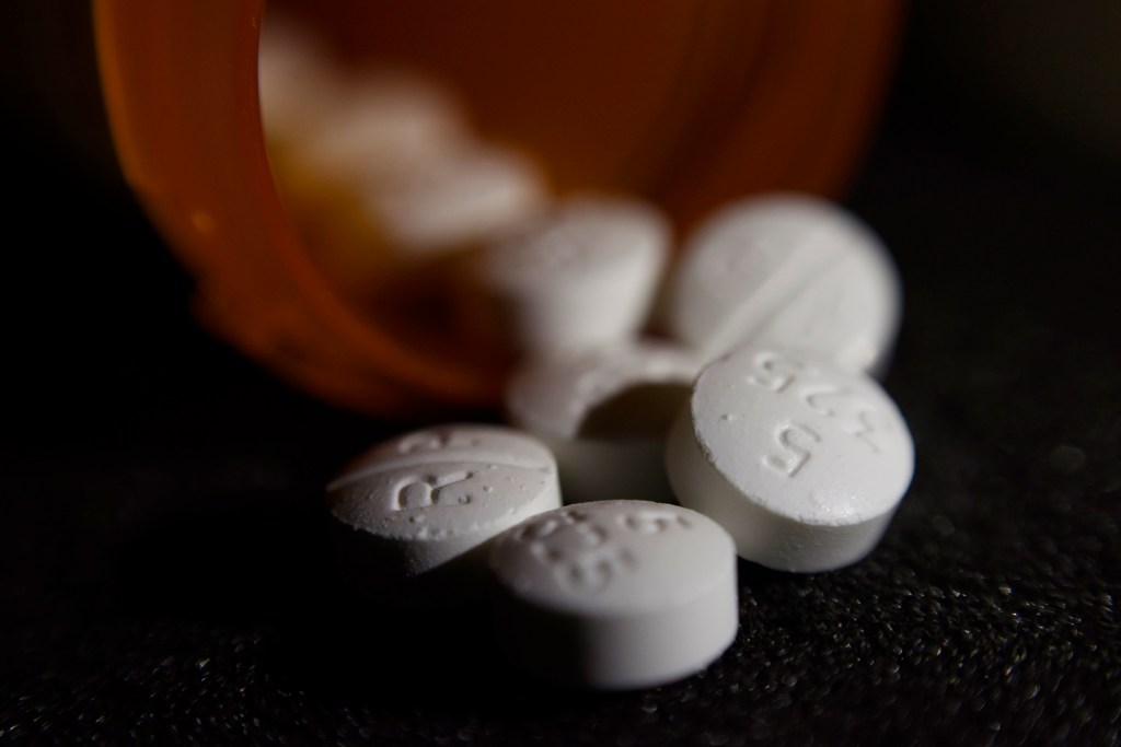 Close-up of opioid pills spilling from a prescription bottle