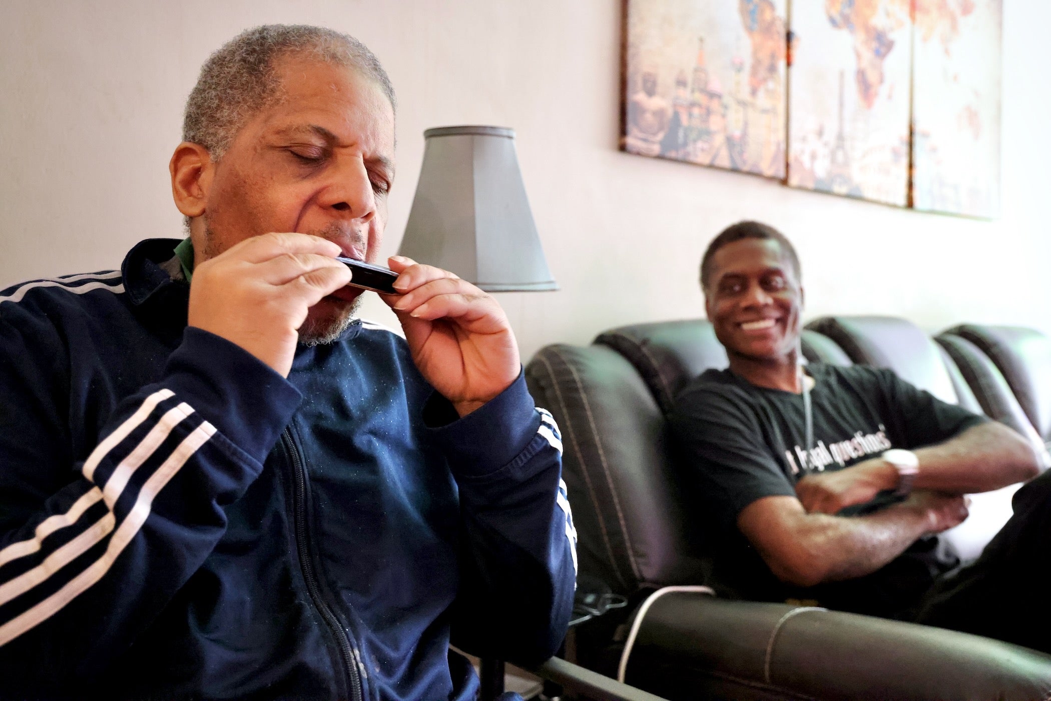 James Henry plays harmonica while sitting next to the Senior Companion Program's Joseph Dennis
