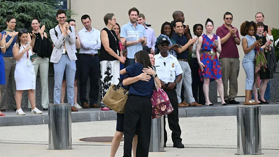 People stand and applaud as people hug 