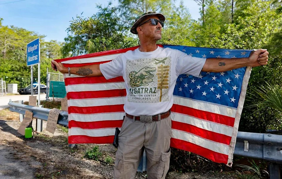 Mark Ribas of Naples, a demonstrator in support of Alligator Alcatraz, stands near the gate entrance to the detention facility. It is within the Florida Everglades, 36 miles west of the central business district of Miami, in Collier County, Florida Saturday, July 12, 2025.