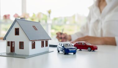 Model home and model cars on a desk with a person writing in the background