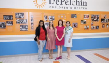 four women stand in front of a DePelchin sign