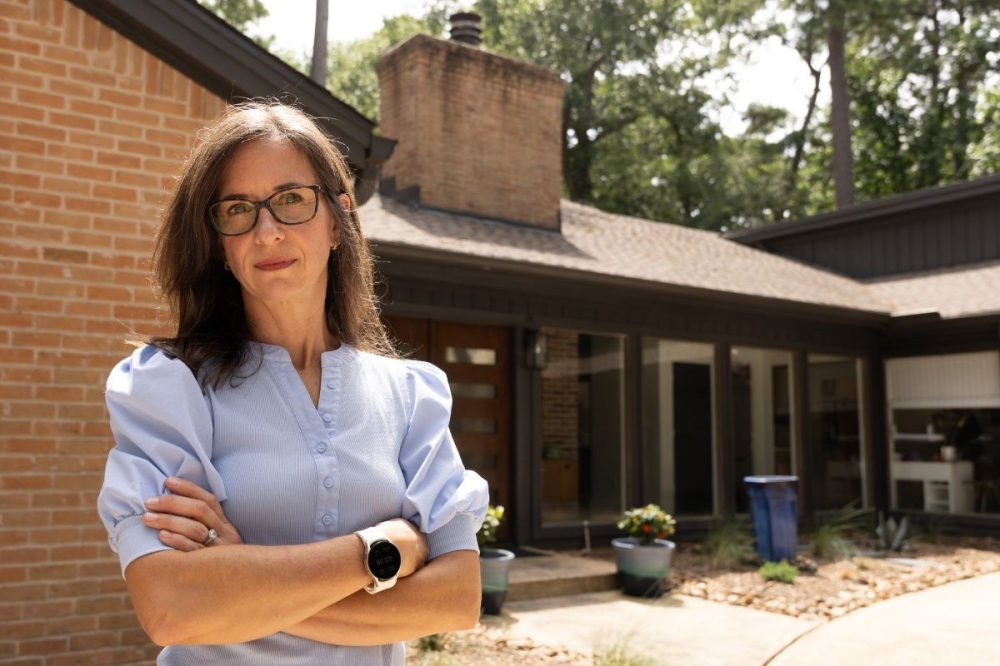 Jennifer Coulter stands in front of her Kingwood home, which was renovated after flooding from Hurricane Harvey in 2017. She said she's seen her insurance rates spike in recent years. (Raphael Fernandez/Community Impact)