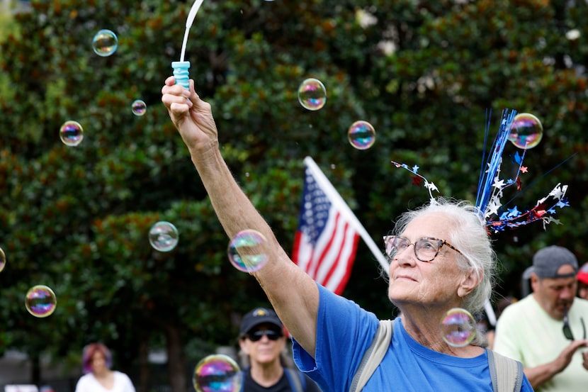 Gretchen Peterson of Dallas makes soap bubbles during a protest hosted by 50501 and...