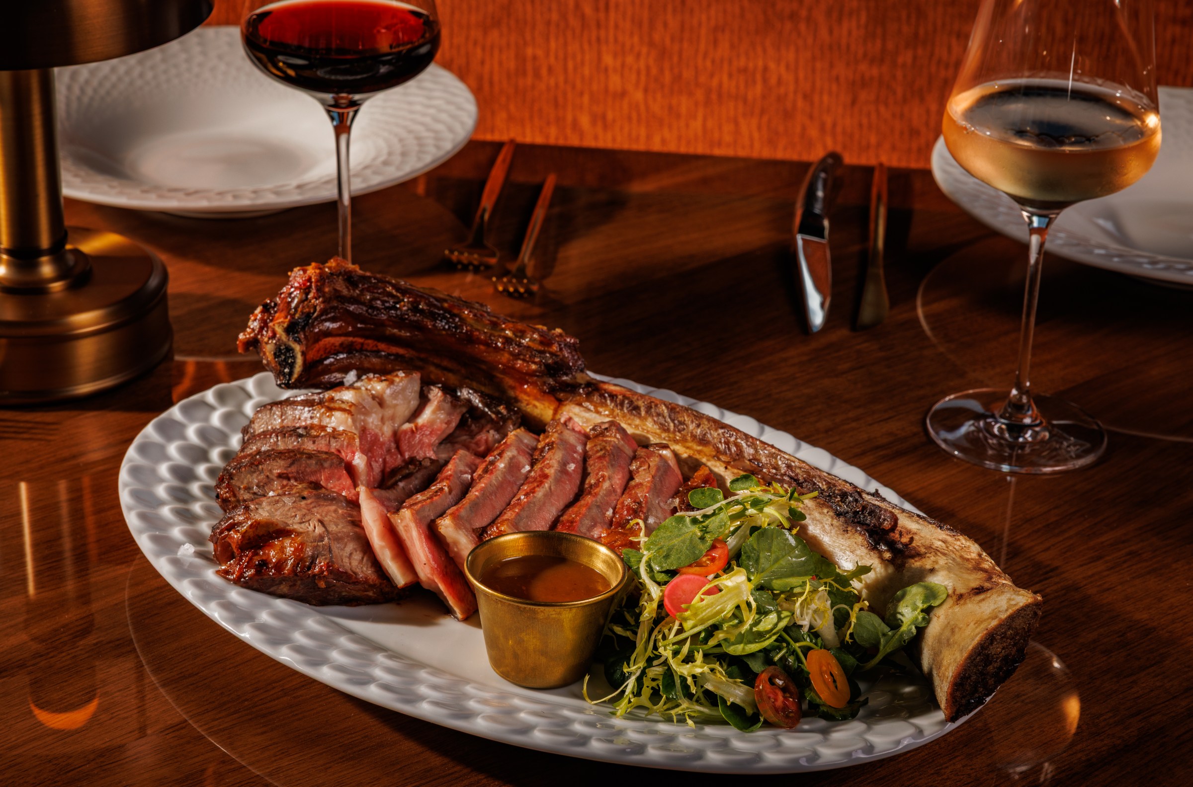 A massive rib-eye sits on a plate, sliced.
