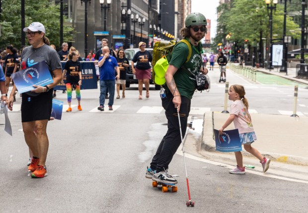 Matt Keeth, who is visually impaired, rides a skateboard with a rolling visual impairment cane during the Disability Pride Parade to celebrate National Disability Pride Day Saturday, July 26, 2025 in the Loop of Chicago. Keeth is also a photographer and seeks to empower kids who have visual impairment. (Dominic Di Palermo/Chicago Tribune)