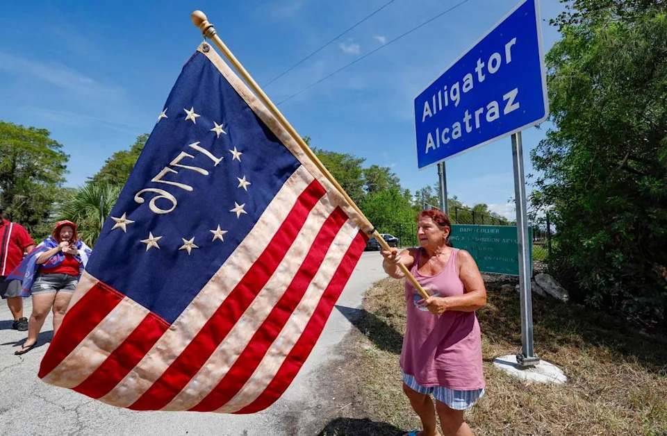 Rena Mourer, who is in favor of Alligator Alcatraz, waves a Betsy Ross 1776 American flag at the front entrance to Alligator Alcatraz as Florida lawmakers and members of Congress tour the detention facility located within the Florida Everglades, 36 miles west of the central business district of Miami, in Collier County, Florida Saturday, July 12, 2025.