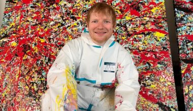 A painting of a man in coveralls kneeling in front of an abstract painting with splatters of red and blue paint.