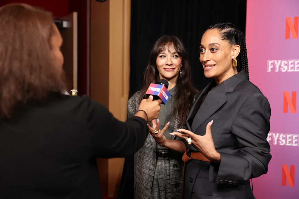 Tracee Ellis Ross being interviewed at a Netflix event with a Rashida Jones standing next to her