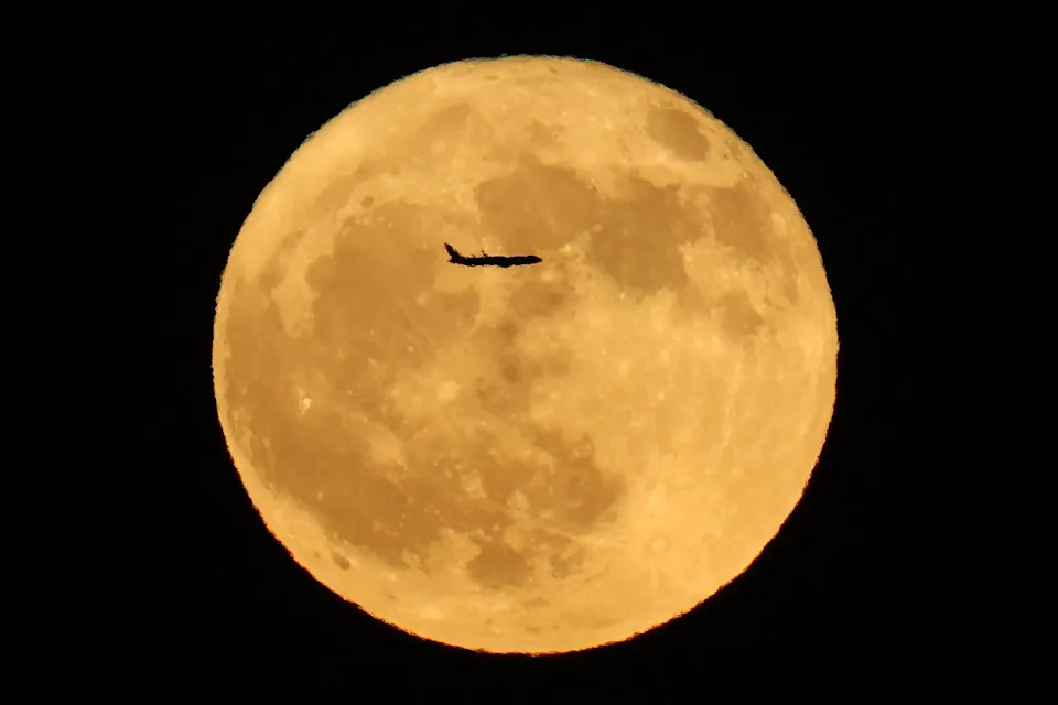 The silhouette of a plane crosses the full buck moon in Adelanto, Calif. 