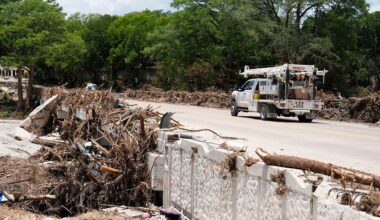 A utility truck drives past debris from a flood in Hunt, Texas on Wednesday, July 9, 2025. (AP Photo/Ashley Landis)