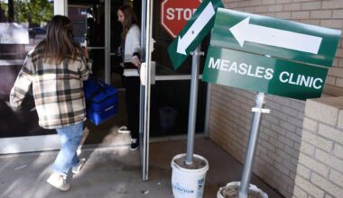 Health department staff members enter the Andrews County Health Department measles clinic carrying doses of the measles, mumps and rubella vaccine, Tuesday, April 8, 2025, in Andrews, Texas. (AP Photo/Annie Rice)