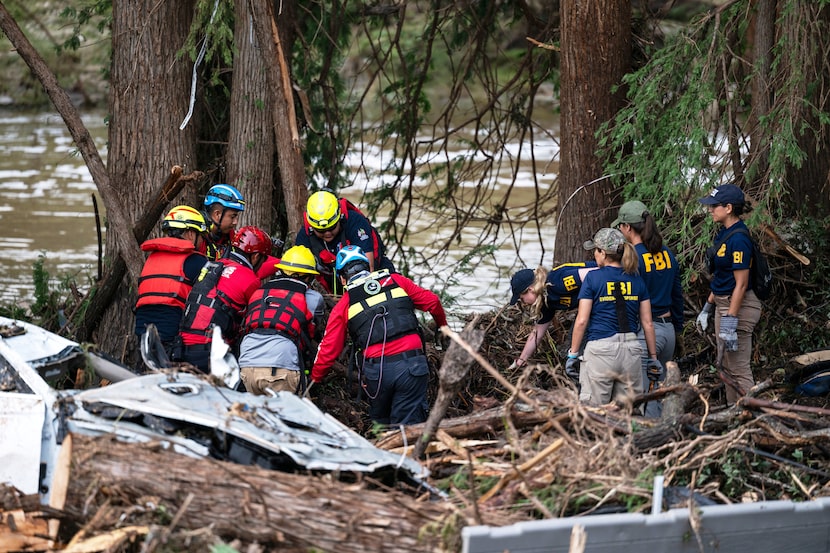 A crew of firefighters from Ciudad Acuna, left, aid in search and rescue efforts near the...