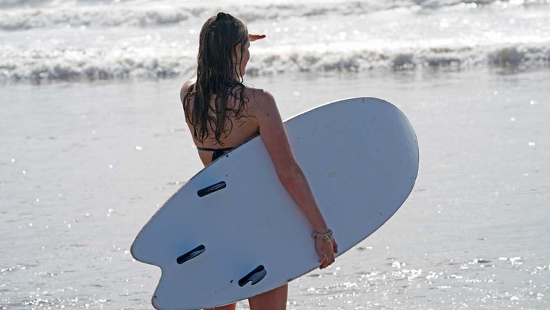 A woman with a board scouts out the waves at near Ocean Beach Pier.