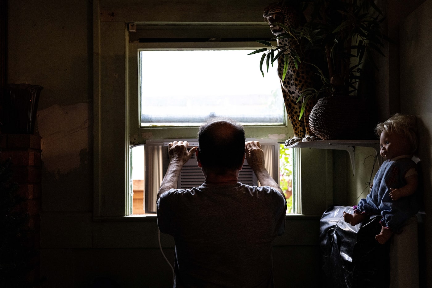 Mario Flores positions an AC unit in the living room window of his North Oak Cliff home on...