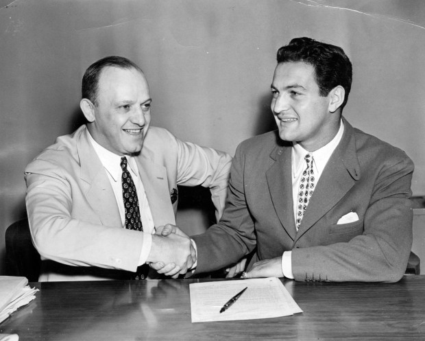 Sid Luckman, right, shakes the hand of Chicago Bears owner George Halas after signing a two-year contract with the Bears in July 1939. Luckman broke out into another smile a bit later when he was told he had been elected to a place on the Tribune's All-Star squad. (Chicago Tribune historical photo)