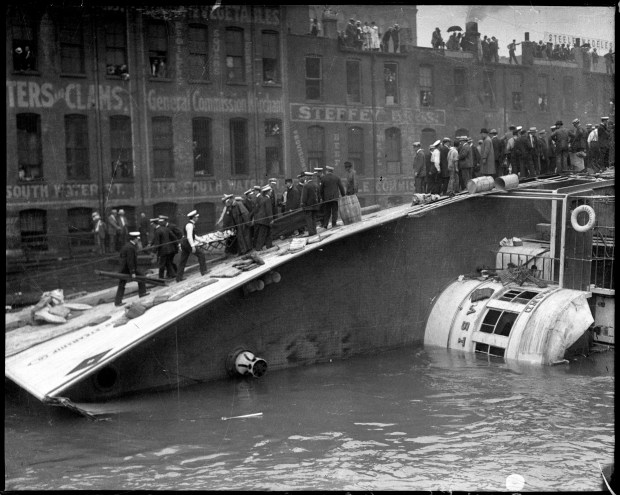 A victim is carried up the SS Eastland as the steamship lies on its side in the Chicago River after slowly rolling over and drowning 844 people July 24, 1915. (Chicago Tribune historical photo)