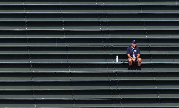 A guest services worker sits alone in the right-field bleachers before a Cubs-Guardians game at Wrigley Field on July 3, 2025, in Chicago. (John J. Kim/Chicago Tribune)